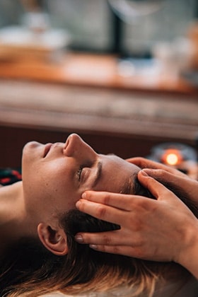 Hands providing therapeutic head massage for stress relief and overall wellness