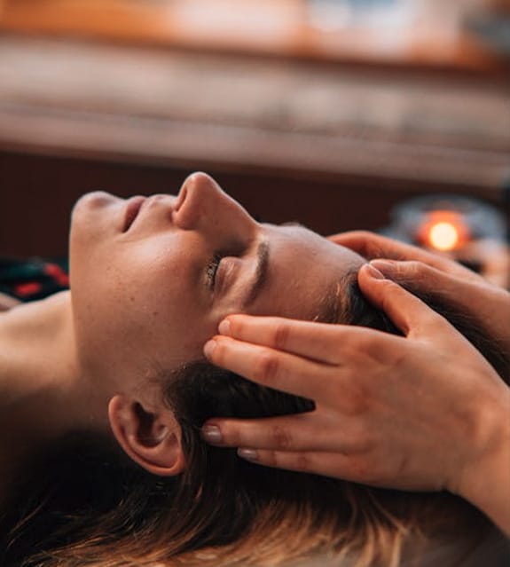 Hands providing therapeutic head massage for stress relief and overall wellness